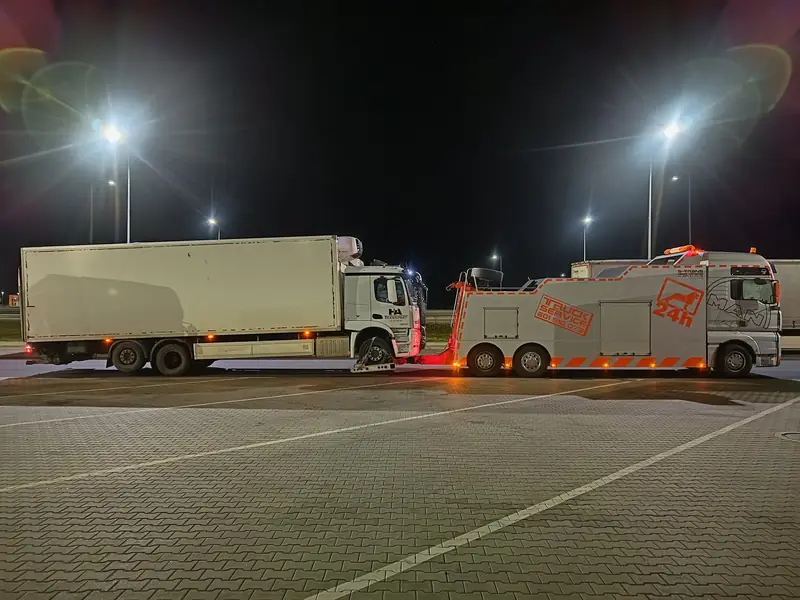 Ciężki holownik S-Trans holuje samochód ciężarowy nocą