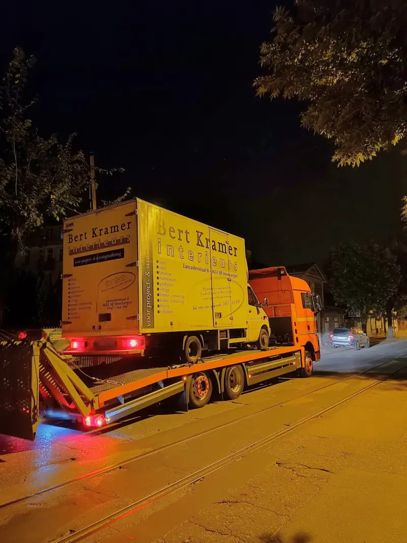 Ciężarowa laweta S-Trans z samochodem dostawczym na platformie, nocą